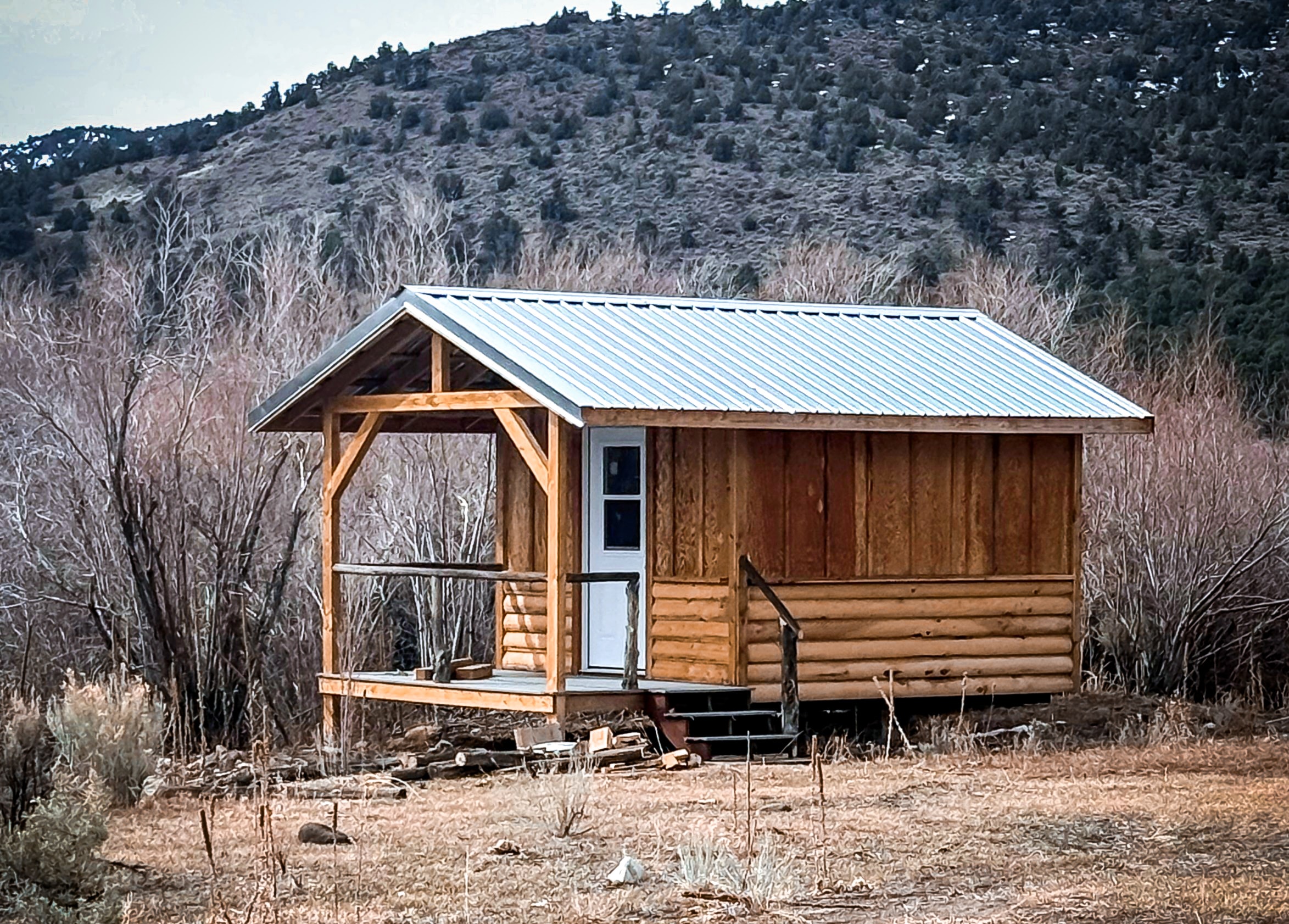 Log cabin in a sage meadow with mountain backdrop